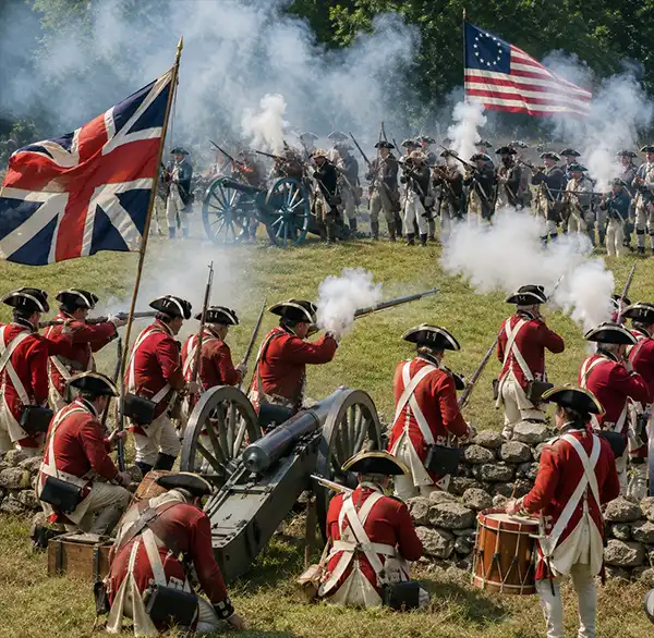 A Revolutionary War battle reenactment features American Patriots and British Redcoats in authentic eighteenth-century uniforms firing muskets and cannons across a smoke-filled field during a historical demonstration.